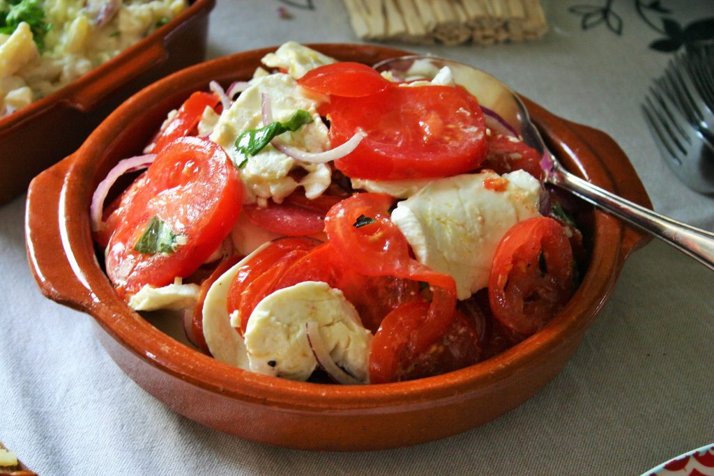 Zomerse Spaanse tomaten salade met mozzarella, knoflook, uienringen, olijfolie en basilicum blaadjes - tapasfeestje - mels Feestje"